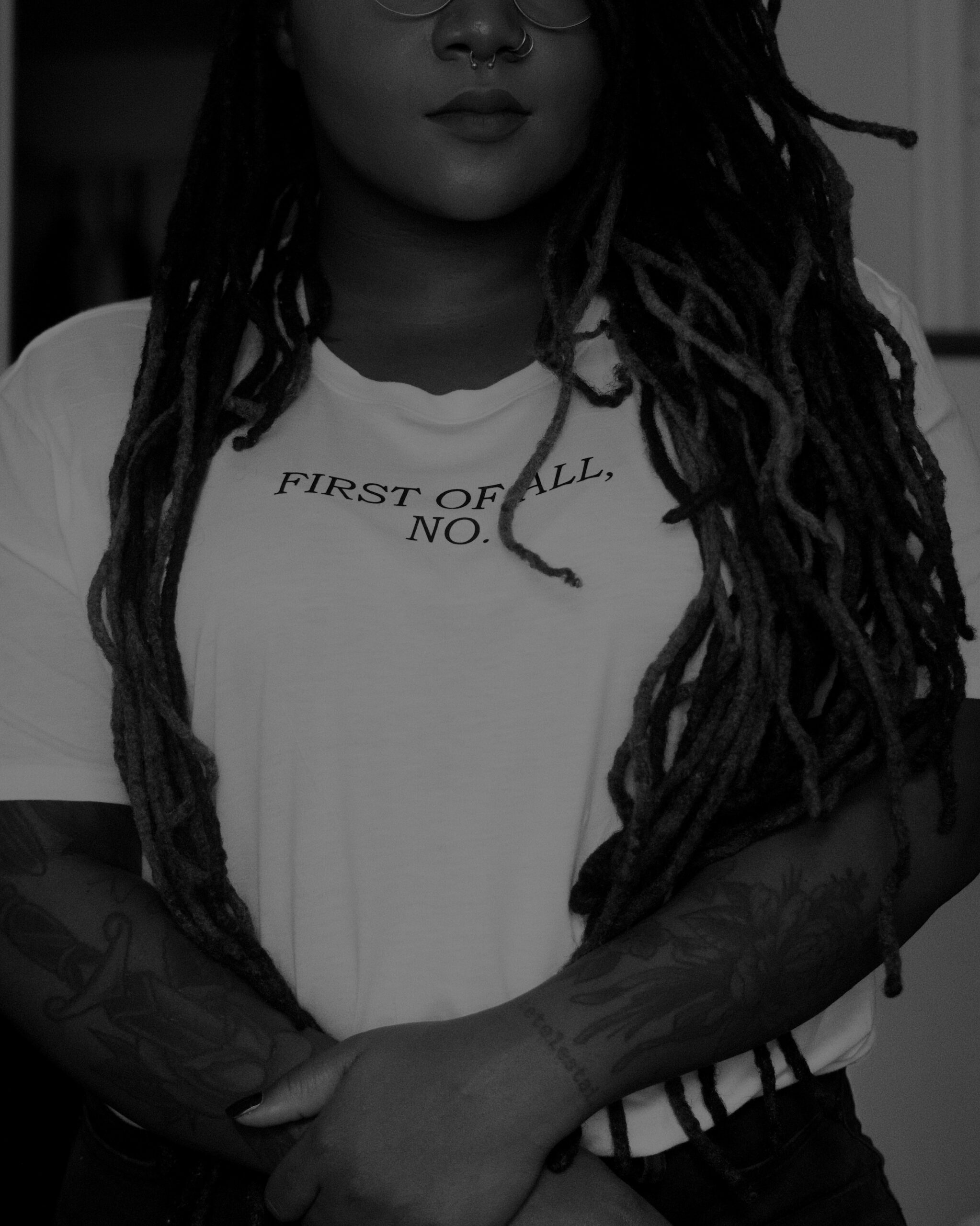 Black woman standing with her arms cross wearing shirt that says "first of all, no"